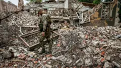 Soldado anda em escombros após bombardeio