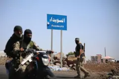 صورة أرشيفية بتاريخ  19 يوليو/تموز 2025 لمسلحين على متن رداجة نارية، وجههما ملثم في في الحي الغربي لمدينة السويداء ذات الأغلبية الدرزية بجنوب سوريا