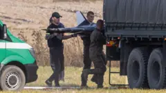 Três homens carregam um drone para dentro de um caminhão.