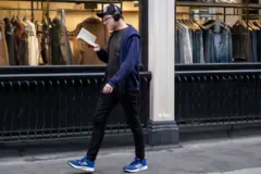 Homem caminhando na rua enquanto lê um livro