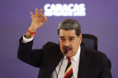Nicolás Madudo gestigula levantando la mano. Lleva una corbata de rayas.