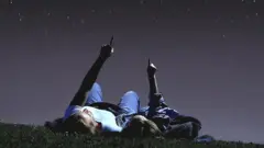 Una madre y su hija mirando hacia el cielo