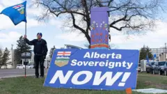 Un partidario separatista sostiene una bandera durante una manifestación cerca de la sede de Elections Alberta en Edmonton, Canadá, el 4 de mayo de 2026