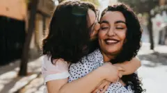 نساء من مجتمع الميم يُعانقن بعضهن البعض في أحد الشوارع 