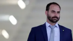 Deputado federal Eduardo Bolsonaro em corredor, olhando para frente