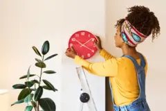 የግድግዳ ሰዓት የምትሰቅል ሴት