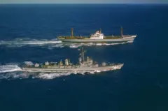 O U.S.S. Barry (à esquerda) navega próximo ao cargueiro soviético Ansov, que saía de Cuba, para inspecionar sua carga. O Barry não enviou pessoal a bordo. O encontro ocorreu a 565 milhas ao norte-nordeste de Porto Rico. A cobertura do Ansov estava carregada de equipamento militar, incluindo oito grandes objetos alongados que pareciam mísseis soviéticos.