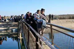 15 Ocak 2026'da Suriye'nin doğusundaki Deyr ez-Hafer'de, Kürt liderliğindeki Suriye Demokratik Güçleri ile cephe hattına yakın, Halep kırsalındaki Cerirat el-İmam köyü yakınlarında bir nehri geçen Suriyeliler görülüyor. 