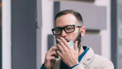 رجل يدخن مرتديا كمامة