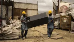 Trabajadores cargan una nevera vieja en las afueras de Ciudad de Guatemala.