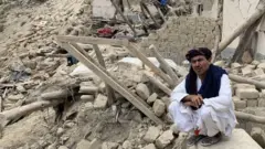 Image shows two men amid rubble
