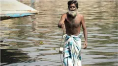 covek magnetom vadi gvozdje iz reke