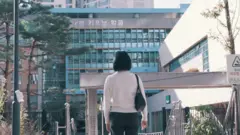 학교 앞에 서 있는 여성의 뒷모습