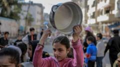 دختر جوان با قابلمه و قاشق در غزه برای غذا صف می‌کشد