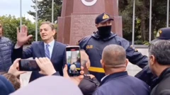 AXCP sədri Əli Kərimli Şəhidlər Xiyabanında sağ əlini yuxarı qaldırıb izdihama müracət edir. Onun yanında polis dayanıb.