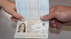 La mano de una mujer y la mano de un hombre sostienen un pasaporte uruguayo abierto en la página que contiene los datos de la persona.