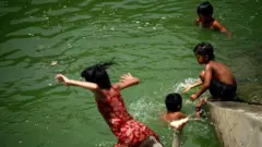 ঢাকার হাতিরঝিলের পানিতে তীব্র গরমের সময় খেলা করছে শিশুরা।