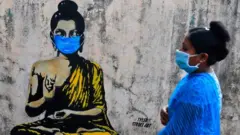 Masked woman walking by graffiti on a wall