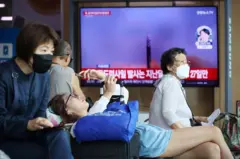 TV 앞에 누워서 핸드폰을 보는 여자