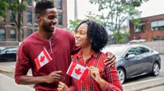 happy young black couple dey celebrate Canada day togeda 