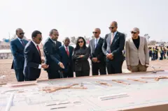 ጠቅላይ ሚኒስትር ዐቢይ ከሌሎች ከፍተኛ ባለሥልጣናት ጋር በመሆን የመሰረት ድንጋይ ከማስቀመጣቸው በፊት የፕሮጀክቱን ዲዛይን ሲጎበኙ