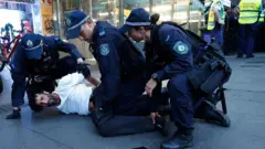 دو نیروی پلیس یک نفر را روی زمین خوابانده به او دستبند می‌زنند