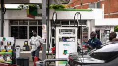 Three pipo stand for inside one Nigeria petrol station