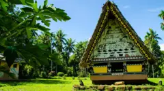 Un edificio tradicional en Palaos con las estructuras principalmente de madera (tablas) y techo muy empinado de paja o palma para facilitar el escurrimiento de la lluvia y permitir ventilación.