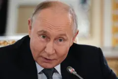 Putin, vestido com um terno escuro, camisa clara e gravata de bolinhas, fala ao microfone, em uma coletiva de imprensa
