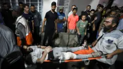 Un hombre herido es llevado en camilla para recibir asistencia después de que un ataque impactara en el hospital Bautista al Ahli.