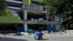 黄緑色の壁の多層階の建物が大きく破損し、壁の大部分が地面に落下している