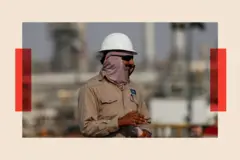 Un trabajador de una plataforma petrolífera, con casco blanco y mono de trabajo color caqui, mira hacia un lado