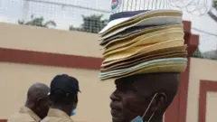 And on Wednesday a hawker in the Nigerian city of Lagos tries to sell hats to protesters opposing calls to reduce the country's minimum wage set at ($65; £45) a month.
