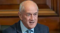 Roelf Meyer dey speak at govment event. E dey wear navy blue suit and light blue tie