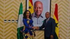 Nigeria and Ghana foreign ministers Bianca Ojukwu and Ablakwa shake hands wit Nigeria and Ghana flag behind dem