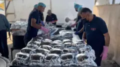 رجال يقفون أمام أطعمة مغلفة في أحد المطابخ العامة