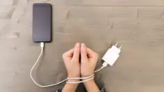 Photo d'une main attachée à un câble téléphonique.