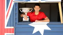 Novak Djokovic holding the 2021 Australian Open championship trophy, February 2021