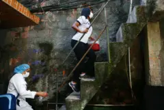 Duas mulheres sobem escada em área externa de casa