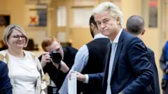 Герт Вилдерс смотрит в камеру, опуская бюллетень в урну.