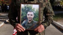A soldier holding a framed picture of Serhiy Tarasyuk
