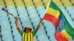 ሓደ ማልያ ሃገራዊት ጋንታ ኢትዮጵያ ተኸዲኑ ባንዴራ ኢትዮጵያ ዘንበልብል ደጋፊ ኣብ ማእከል ስታድዩም