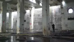 Pessoa tirando fotografias em um edifício vazio de altas colunas na central nuclear de Lemóniz, na Espanha