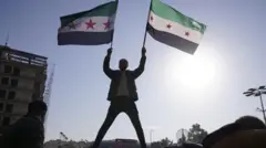 A man holds the Syrian opposition flag as they celebrate after Syria's army command notified officers on Sunday that President Bashar al-Assad's 24-year authoritarian rule had ended ජනාධිපති බෂාර් අල්-අසාද්ගේ 24 වසරක ඒකාධිපති පාලනය අවසන් වූ බව සිරියාවේ හමුදා අණදෙන නිලධාරීන්ට ඉරිදා දැනුම් දීමෙන් පසු මිනිසෙක් සිරියානු විපක්ෂ ධජය අල්ලාගෙන සිටී.