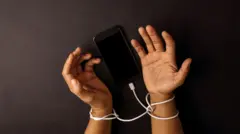 በቻርጀር ገመድ የታሰሩ እጆች