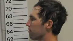 Perfil de Tyler Robinson olhando para a esquerda, com uma fita métrica de altura