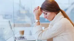 컴퓨터 앞에서 머리를 감싸쥐고 있는 여성