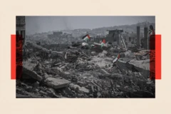 Pilas de escombros en Gaza sobre las que se ven banderas palestinas. Al fondo se ve el terreno totalmente destruido y tapado de escombros entre ruinas de edificios