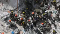 Equipes de resgate procuram por pessoas desaparecidas sob os escombros