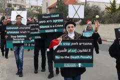 Палестинские и израильские активисты собрались на акции протеста в декабре против тогдашнего проекта закона, который предусматривал смертную казнь для палестинцев, осужденных за убийство израильских граждан, недалеко от Бейт-Джалы на оккупированном Израилем Западном берегу.